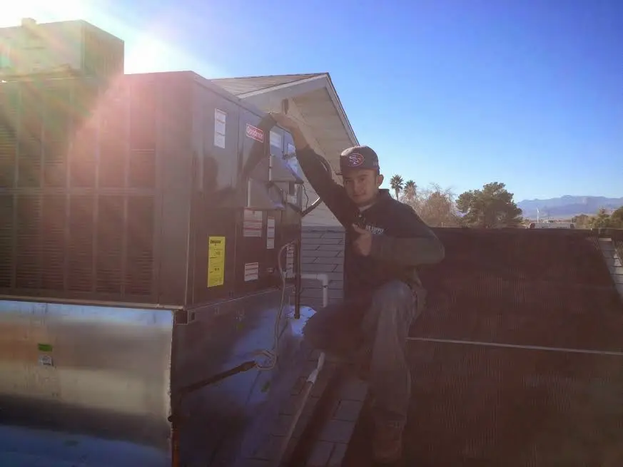 HVAC technician performing Air Duct Cleaning on a rooftop unit in Everman